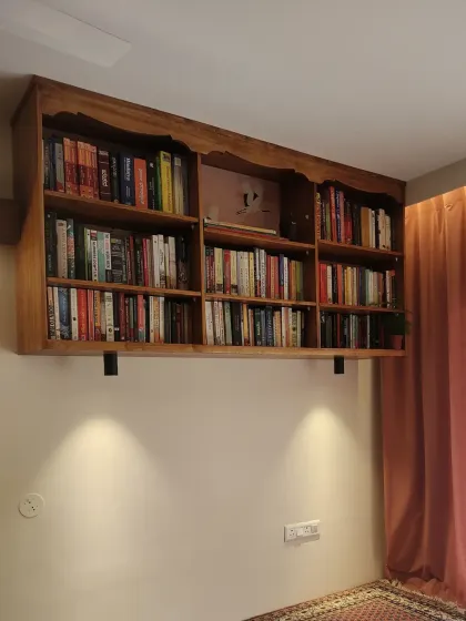 The bookshelf illuminated by spotlights, creating a warm and inviting atmosphere in the evening.