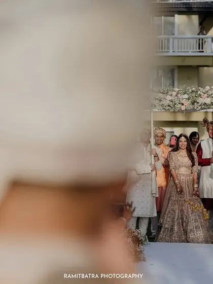 A creative shot from behind the groom's shoulder as he sees his bride for the first time at the end of the aisle.