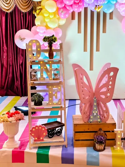 Another detail shot from the twins' party, showing the 'ONE' marquee letters on a shelf and a large pink butterfly prop.