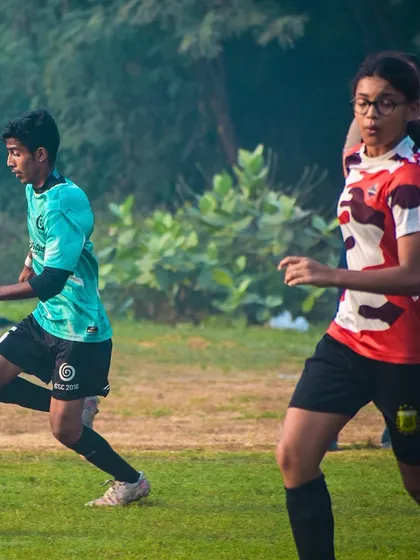 A female player tracks back to defend, showcasing the inclusive and competitive environment.