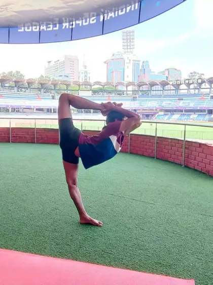 Performing Natarajasana, or Lord of the Dance Pose, against the backdrop of the stadium. This posture is a deep backbend and standing balance that opens the shoulders and chest.