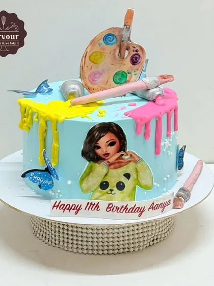 Another take on an art-themed cake, this one features a colorful paint drip, an artist's palette, and brushes. The addition of an edible character print makes it extra special for the birthday girl.