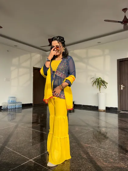 A fun, candid moment in a bright yellow sharara. Wedding functions are all about color, laughter, and making memories.