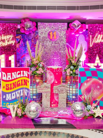 An elaborate stage setup for the 11th birthday disco party, featuring multiple sequin panels, neon signs, and themed props.