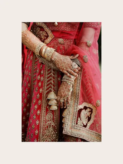 A duplicate of a close-up of the bride's hands, showcasing her intricate henna, bangles, and the detailed embroidery of her lehenga.