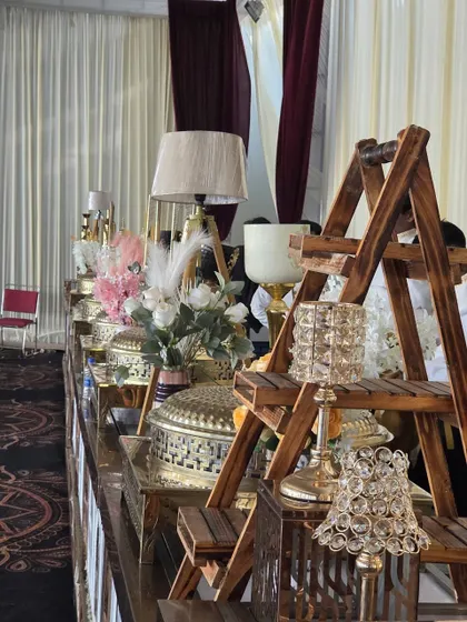 Our wedding buffet setups are a blend of function and artistry. This display features a rustic wooden ladder shelf for serving ware, crystal candle holders, and elegant floral arrangements, adding a decorative touch to the food service.