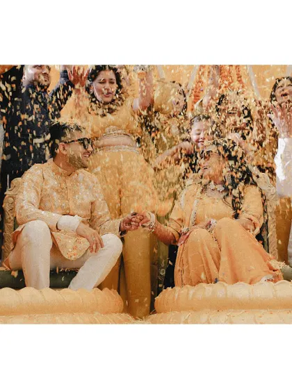 A beautiful shot of the couple holding hands while being showered with a cascade of flower petals.