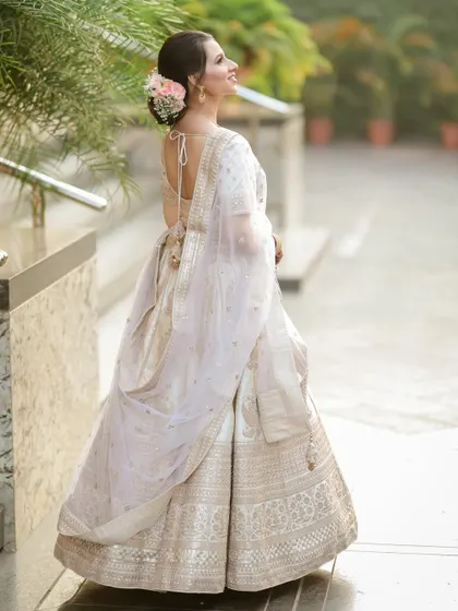 A back profile of the bride, showcasing her beautiful hairstyle with fresh flowers and the elegant drape of her dupatta.