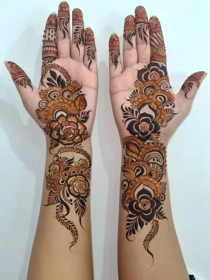 For a modern and bold statement, I love creating Arabic-style henna. This design features prominent floral vines that flow elegantly along the hands, leaving open space to make the pattern pop.