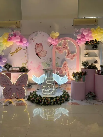 A pastel rainbow butterfly theme with a central floral arrangement and a large butterfly-shaped table.