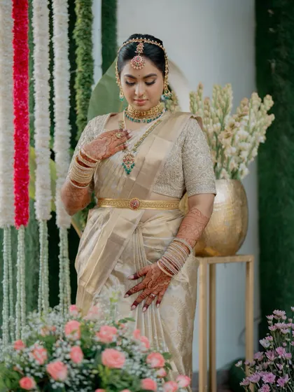 A bride looks down, showcasing her intricate temple jewelry and the beautiful texture of her golden silk saree. Every element of her look was carefully considered and crafted.