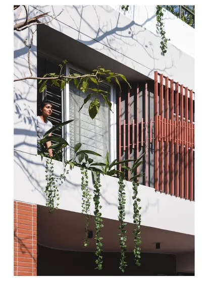 The cascading plants from the upper balcony add another layer of green to the facade, softening the modern lines of the architecture.