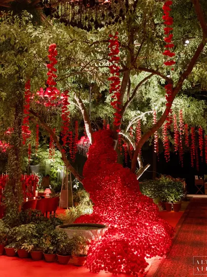 The 'Laal Bagh' reception was inspired by the timeless beauty of heritage palaces and their lush gardens. This corner shows how we used red florals cascading from trees to create a whimsical, magical experience.