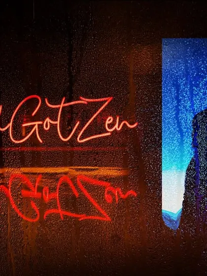 A creative monsoon-themed engagement portrait. The couple's silhouette is seen through a rain-streaked surface, with their neon hashtag reflected, creating a moody and romantic vibe.