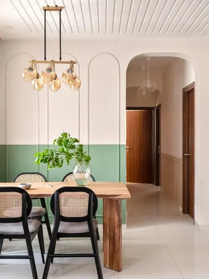 A full view of the dining corner, showing the dual-tone wall with arched beadings, the fluted false ceiling, and the beautiful wooden dining table from Freedomtree.