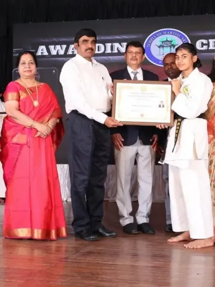 A female black belt recipient with her family and instructors. We celebrate these achievements as a community, honoring the dedication of both the student and their support system.