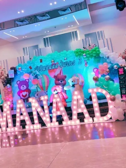 A cute teddy bear-themed 2nd birthday party. The stage features a pastel-colored backdrop and large marquee letters for the name "MANAAD".