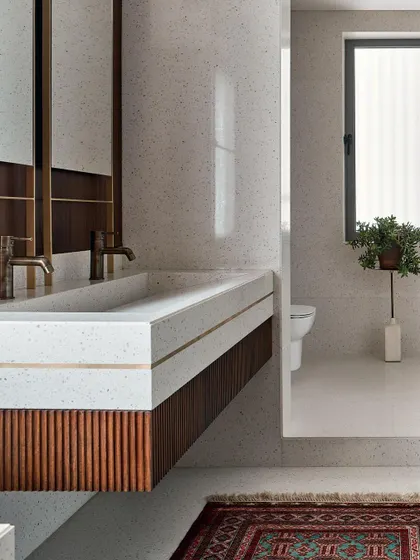 Details matter, especially in a master bathroom. Here, I used a custom terrazzo vanity with brass inlay, paired with fluted wood cabinetry and a vintage-style rug. It's a blend of modern materials and classic textures for a timeless appeal.