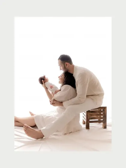 In color, this newborn portrait feels soft and gentle. The all-white outfits and background create a pure and serene atmosphere for these first family photos.