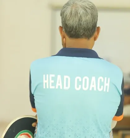 A head coach, seen from the back, addresses his team. Leadership and strategy are as important as skill.