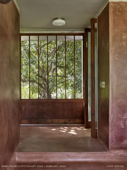 A view through a doorway at Villa Uma, where the dappled light filters through a large mango tree. The architecture is designed to frame the landscape, making the natural surroundings a constant feature of the interior experience.