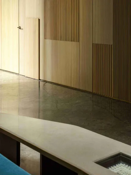 The wooden fluted and veneer paneling is shown in detail, highlighting its texture and the precision of the craftsmanship. This paneling cleverly conceals the doors to the powder room and kitchen.