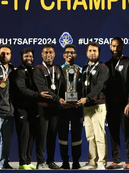 The coaching and support staff of the Indian U17 team with the championship trophy. This highlights the team behind the team, whose work is essential for success.