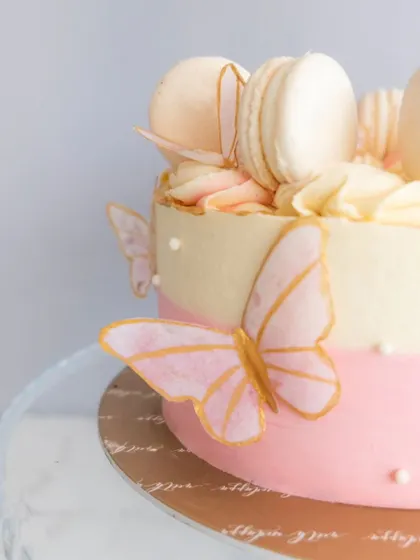 This elegant celebration cake is perfect for so many occasions. It features a two-tone pink and white buttercream finish, adorned with delicate, edible butterflies and a crown of my classic macarons.