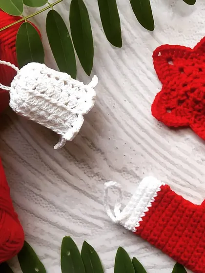 A flat-lay of our red and white Christmas ornaments. This set includes a crochet bell, a star, and a mini stocking, perfect for a cohesive color theme on your tree or as festive gift toppers.