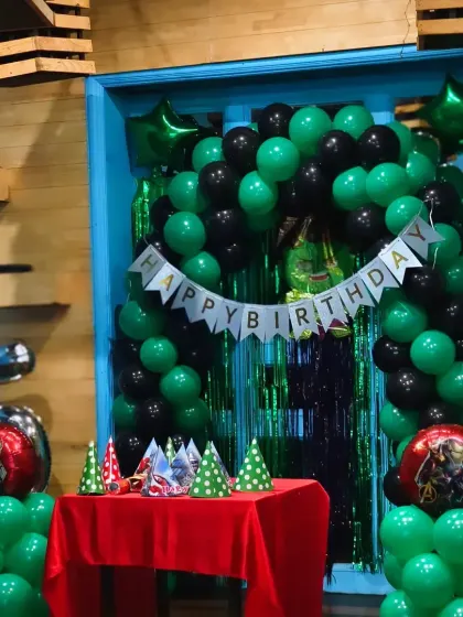 A simple and clean green and black balloon arch, ideal for a superhero or gaming-themed birthday party.