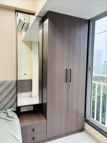 This compact wardrobe unit includes an integrated dressing table with a large mirror and drawers, making it a complete storage and grooming solution for the bedroom.