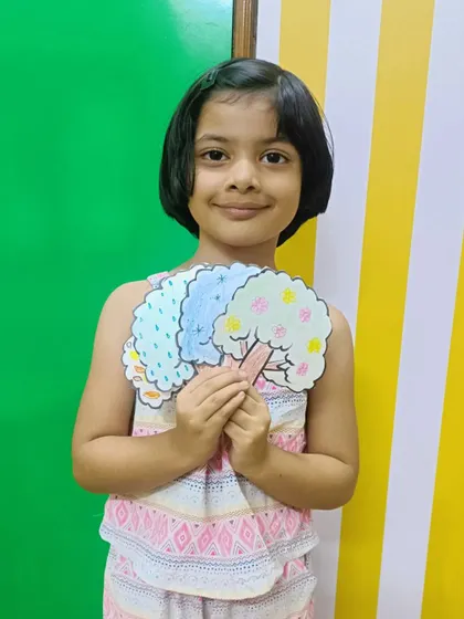 A smiling girl with her beautiful artwork depicting the four seasons.