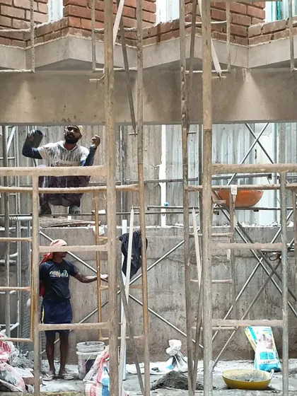 Workers framed by scaffolding at the Brick House site. This image celebrates the human effort and craft that bring our architectural visions to life.