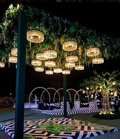 A modern and graphic dance floor under a canopy of greenery and chandeliers.