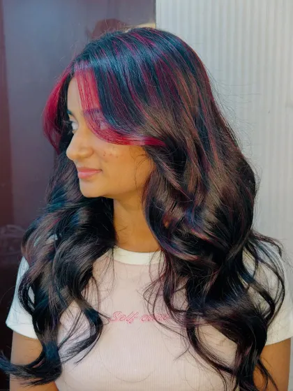 The side profile of the cherry red highlights shows how they blend with the dark hair for a striking contrast.