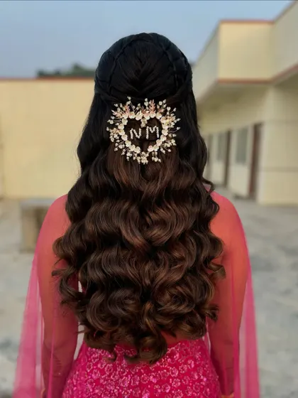 A personalized half-up style with beautiful waves. The heart-shaped accessory features the couple's initials, making it a truly special and romantic detail.