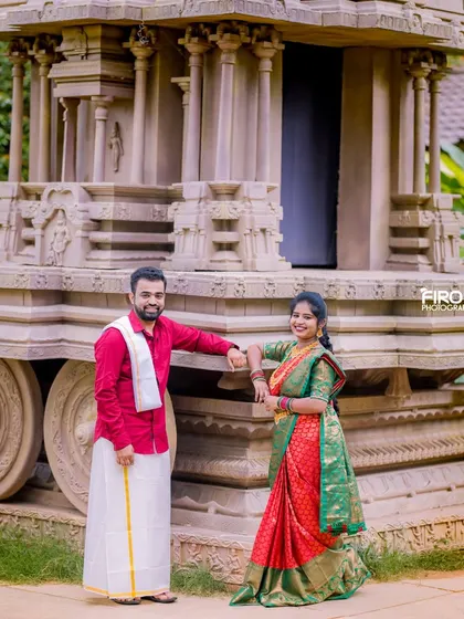 A relaxed portrait of a couple by a stone chariot. Their traditional South Indian attire looks beautiful against the classic, heritage backdrop.