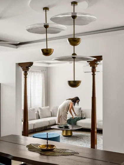 A view from the dining area into the living room, framed by traditional wooden pillars. This design choice helps define the space within an open floor plan while adding a touch of Indian heritage.