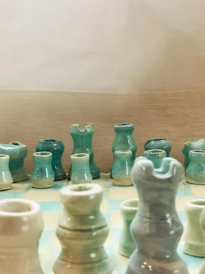 A close-up of the "Cocoa Clash" chess game in progress. The soft green and cream colors of the board and pieces are calming and beautiful.