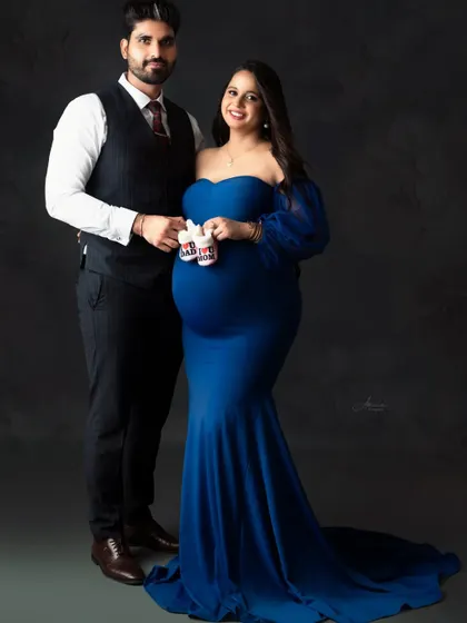 A classic and formal couple's portrait. The dad-to-be's vest and the mom's royal blue gown create a sophisticated look, made even sweeter with the baby shoes.