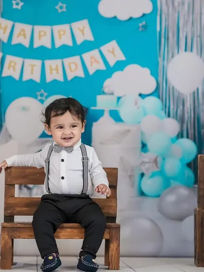 A happy little boy celebrating his first birthday. His joyful smile is the centerpiece of this festive studio setup.