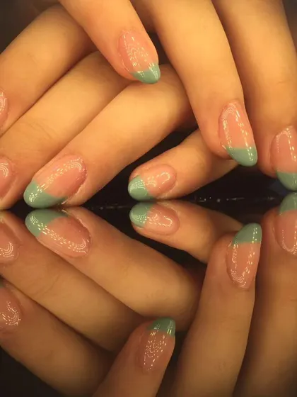 A simple yet stylish French manicure with light green tips on beautifully shaped almond nails.