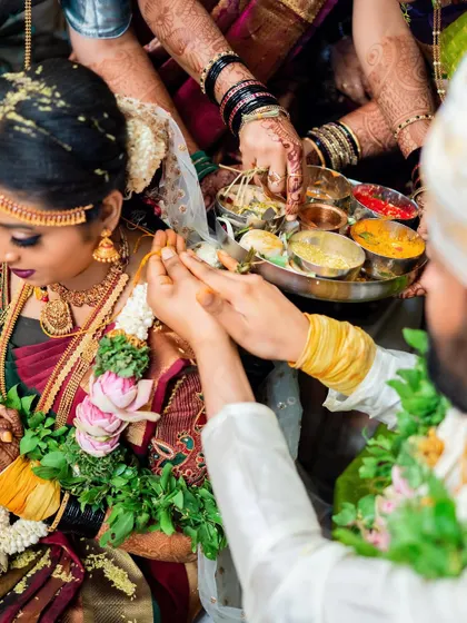 A close-up shot of a wedding ritual, focusing on the hands and the offerings.