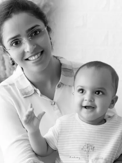 A black and white portrait of a mother holding her happy, waving baby boy.
