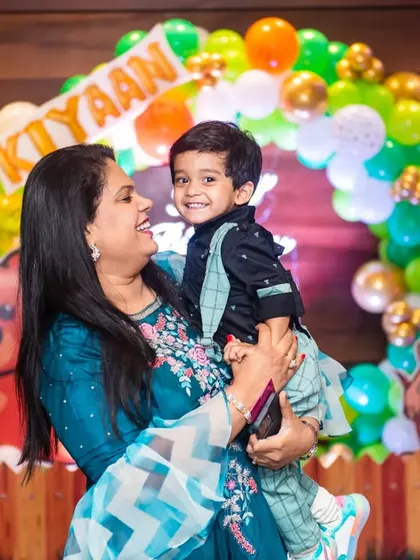 A sweet portrait of a mother holding her son at his second birthday party. The colorful jungle-themed background adds a sense of fun and adventure to the photo.