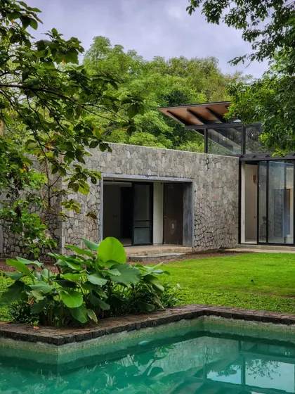 Water, sun, and plant life are the core elements of our tropical homes. This view captures the essence of the Villa in a Grove, where the pool is surrounded by lush greenery and stone walls.