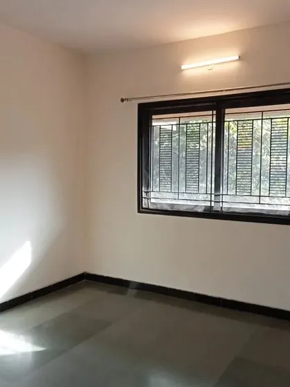 An empty room with freshly painted neutral walls and a dark-framed window. This is the perfect blank canvas for a new homeowner or a room refresh.