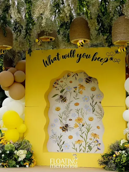 The main photo backdrop was a highlight of the event. A bright yellow wall with the question 'What will you bee?' featured a beautiful floral insert, framed by balloons, daisies, and hanging handmade beehives.