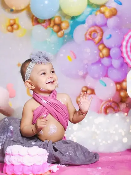 Naysha is clapping with glee in her Candyland-themed cake smash. The colorful setup with donuts and balloons makes the photos extra sweet.