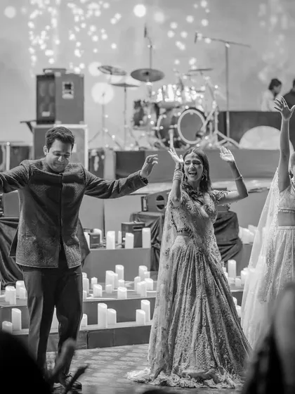 A candid black and white photo of the family enjoying the sangeet. It captures the pure, unchoreographed joy of the celebration.